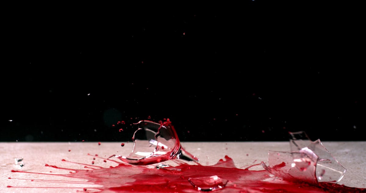 A glass of wine falling and breaking into shards against a black background